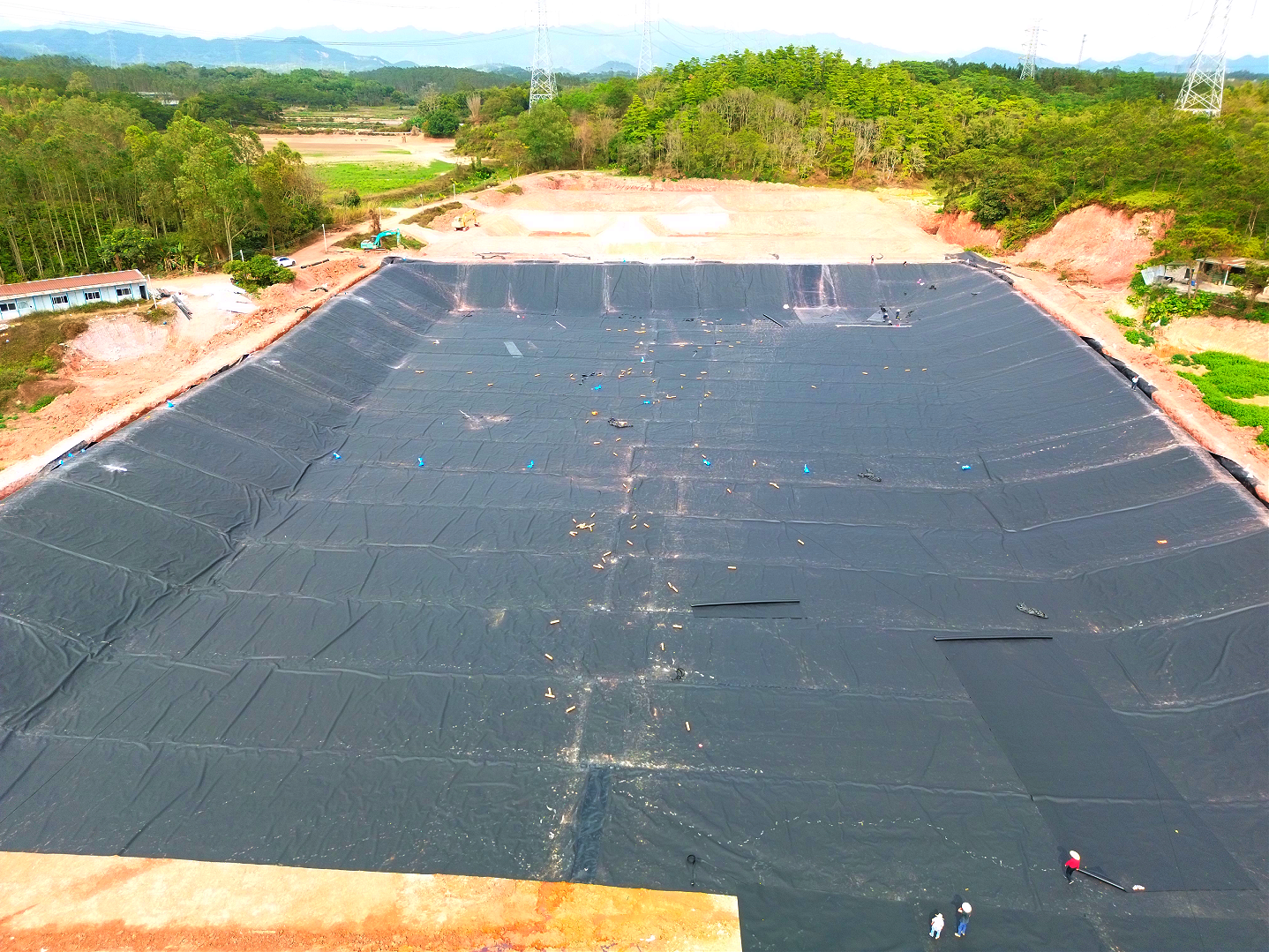 Workers laying HDPE geomembrane on a dam slope