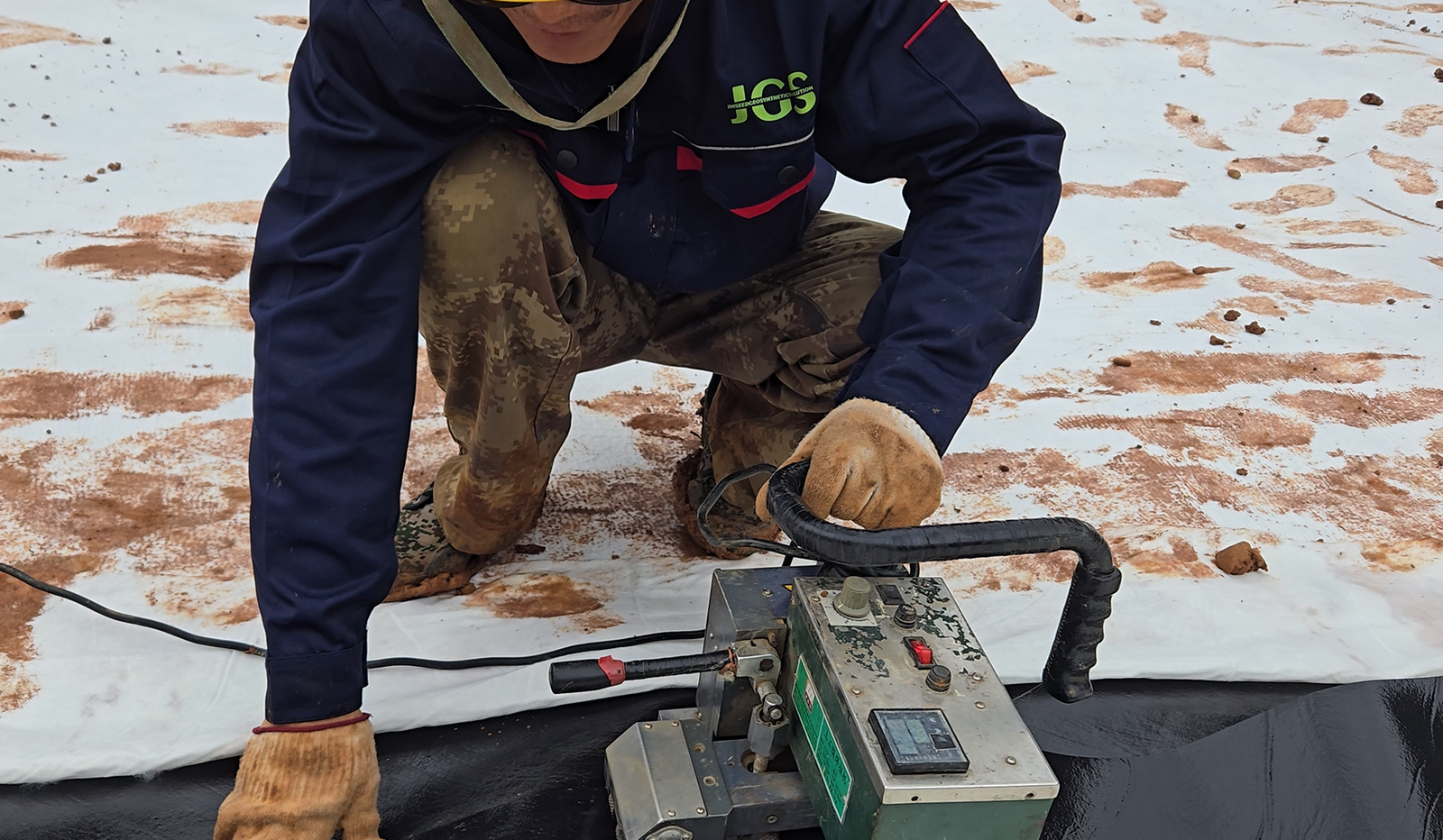 A technician testing a welded geomembrane seam on a lined canal site