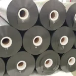 Black geomembrane rolls stacked in a factory storage area