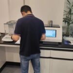 Technician working at a laboratory bench with a balance and testing equipment