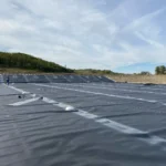 Geomembrane panels with field markings across a lined basin during installation