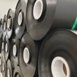 Close view of black geomembrane rolls with white cores in factory storage