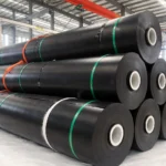 Black geomembrane rolls stacked and strapped inside the factory