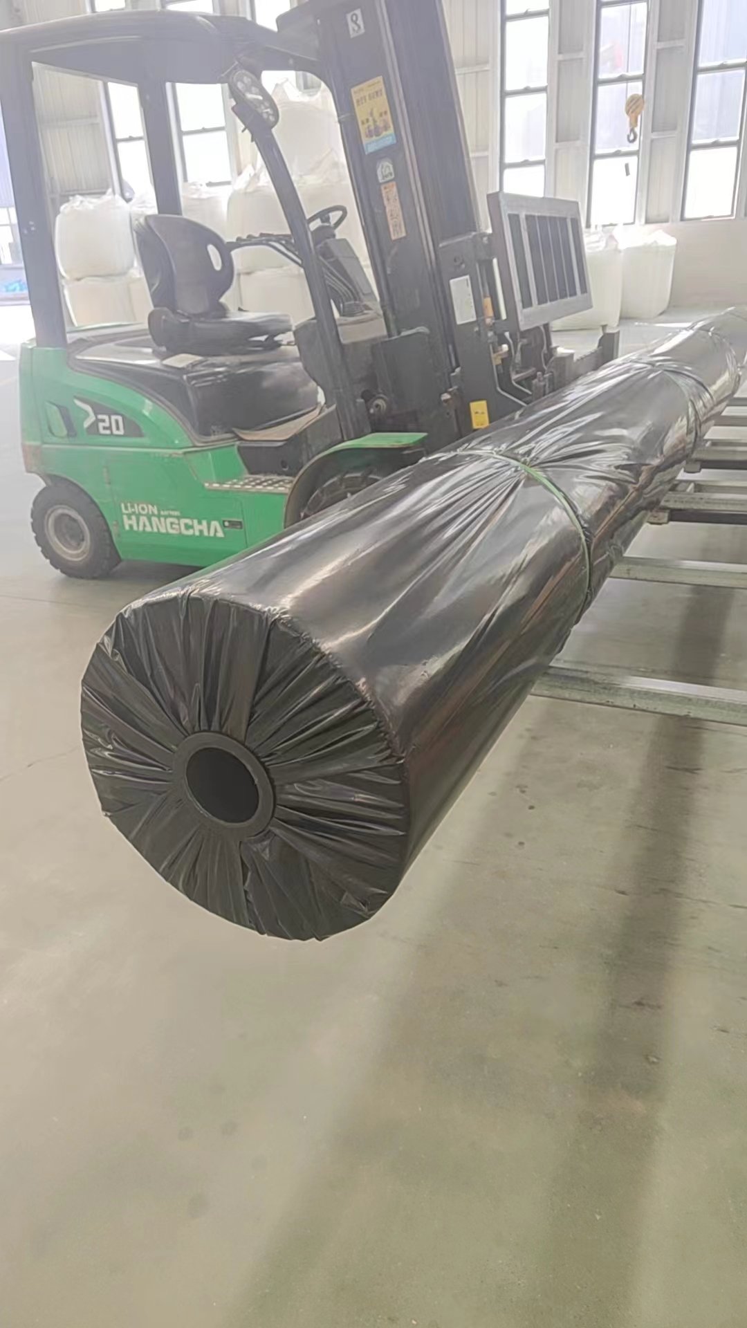 Forklift handling a wrapped geomembrane roll
