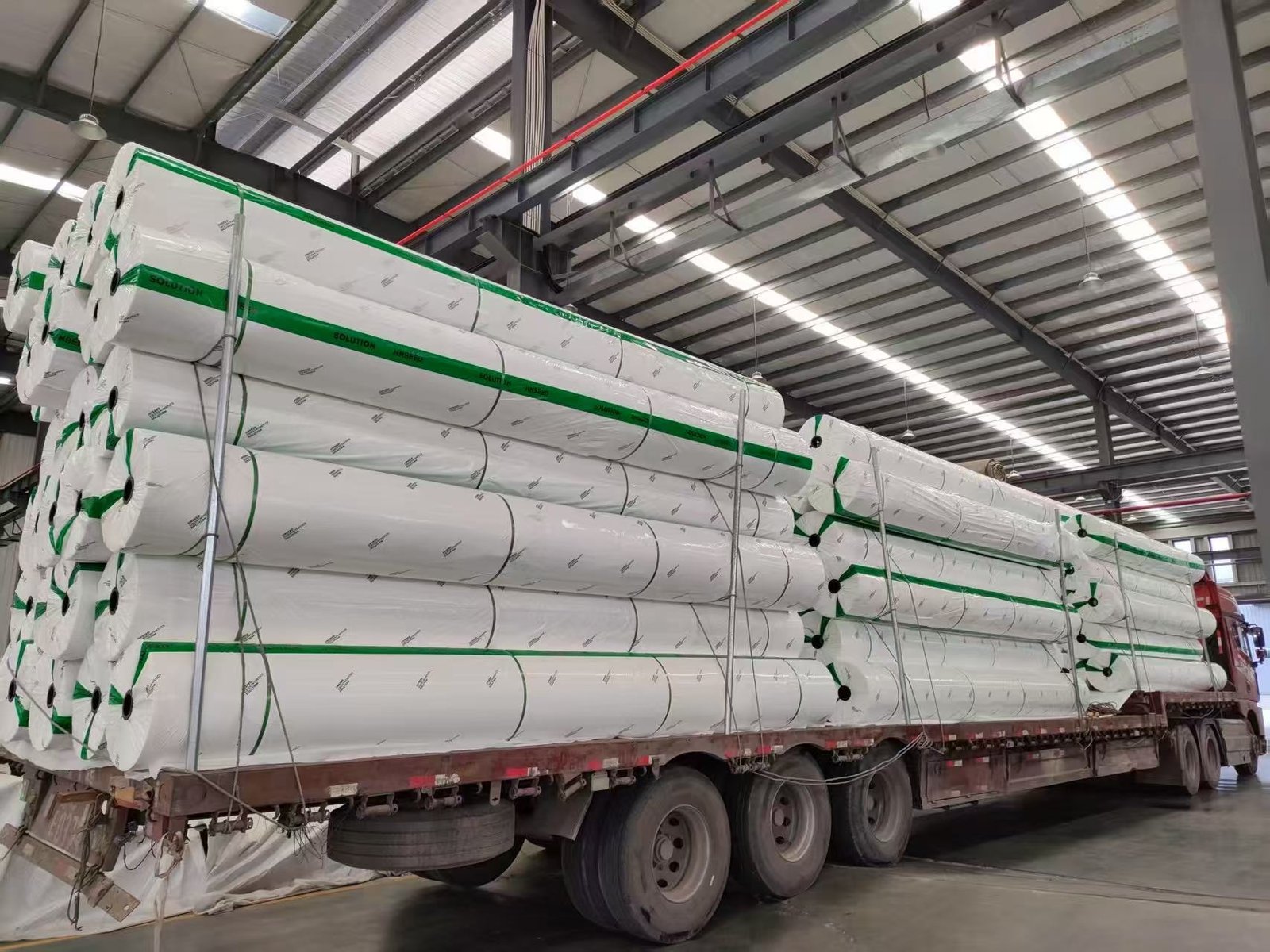Jinseed-branded wrapped geotextile rolls secured on a flatbed truck inside the factory