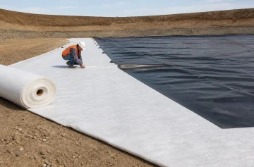 Worker installing a nonwoven geotextile cushion beside an HDPE geomembrane liner