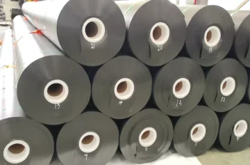Black geomembrane rolls stacked in a factory storage area