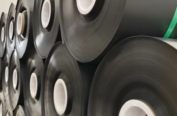 Close view of black geomembrane rolls with white cores in factory storage